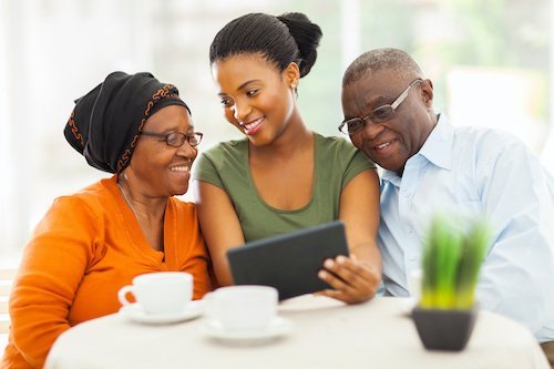 Young girl teaching her senior parents how to use a tablet